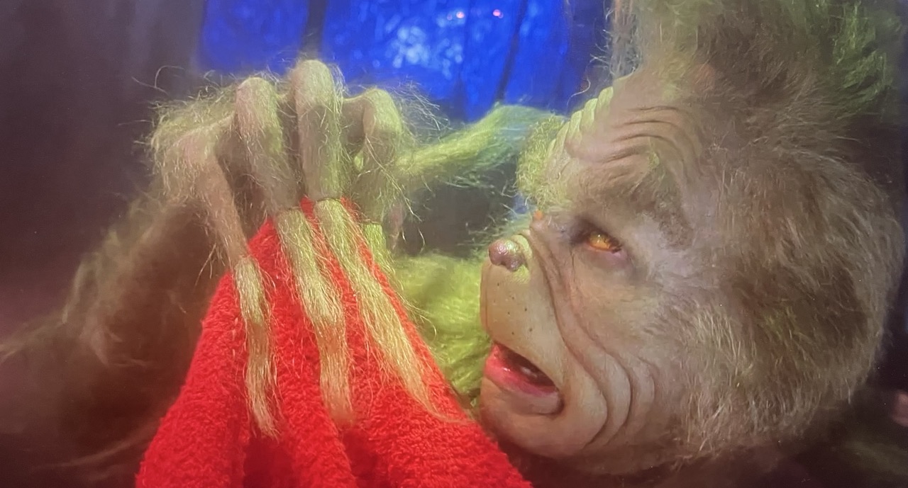 Grinchen-som-syr-stoff-på-fingrene-sine